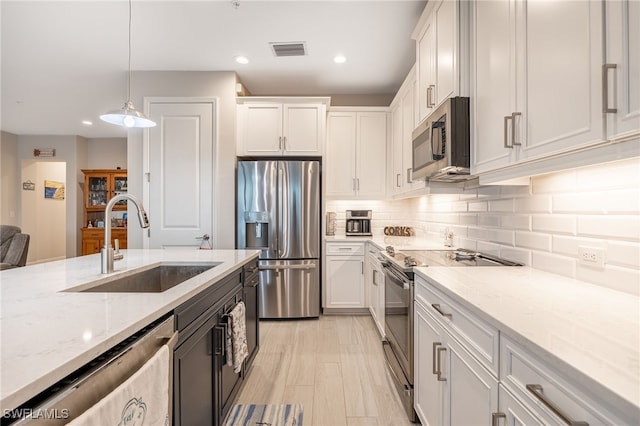 kitchen featuring pendant lighting, sink, white cabinetry, and stainless steel appliances