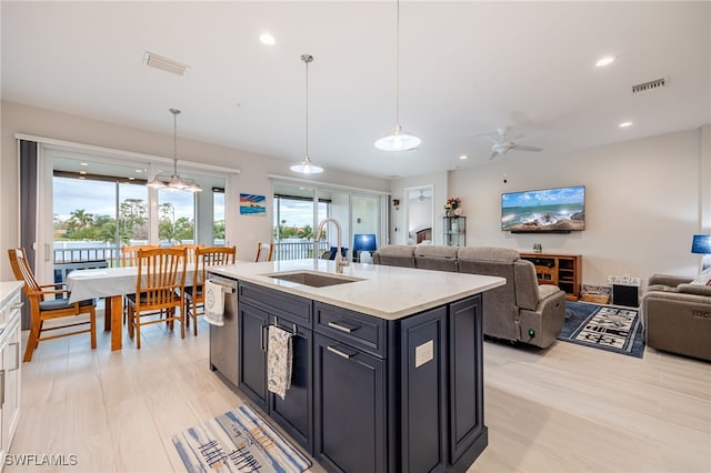 kitchen featuring ceiling fan, dishwasher, pendant lighting, a center island with sink, and sink