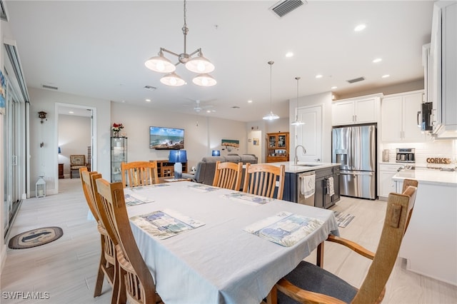 dining room featuring sink, ceiling fan with notable chandelier, and light hardwood / wood-style floors