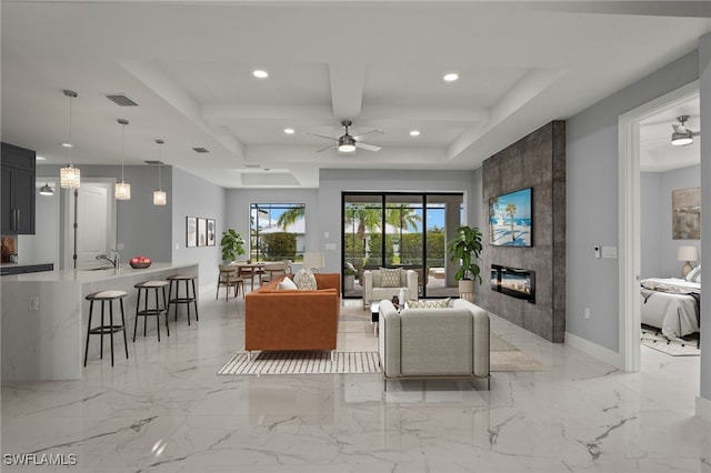 living room featuring ceiling fan, sink, beamed ceiling, and a fireplace