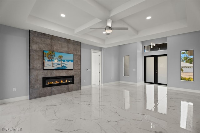 unfurnished living room with a tiled fireplace, coffered ceiling, ceiling fan, and french doors