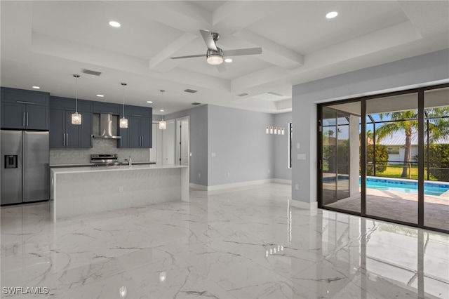 kitchen featuring pendant lighting, tasteful backsplash, wall chimney range hood, a center island with sink, and stainless steel appliances