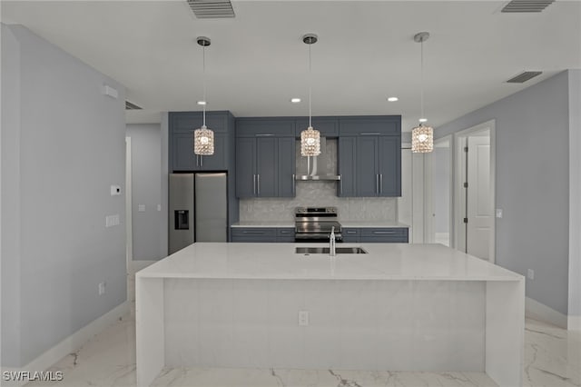 kitchen featuring appliances with stainless steel finishes, sink, backsplash, light stone countertops, and an island with sink