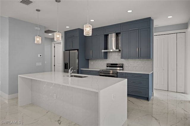 kitchen with wall chimney range hood, stainless steel appliances, an island with sink, sink, and hanging light fixtures