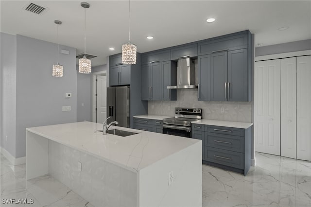 kitchen with pendant lighting, sink, a kitchen island with sink, wall chimney range hood, and stainless steel appliances