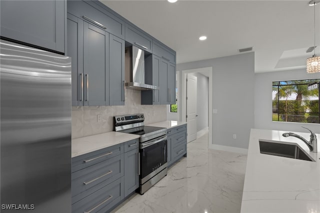 kitchen with hanging light fixtures, sink, backsplash, stainless steel appliances, and wall chimney exhaust hood