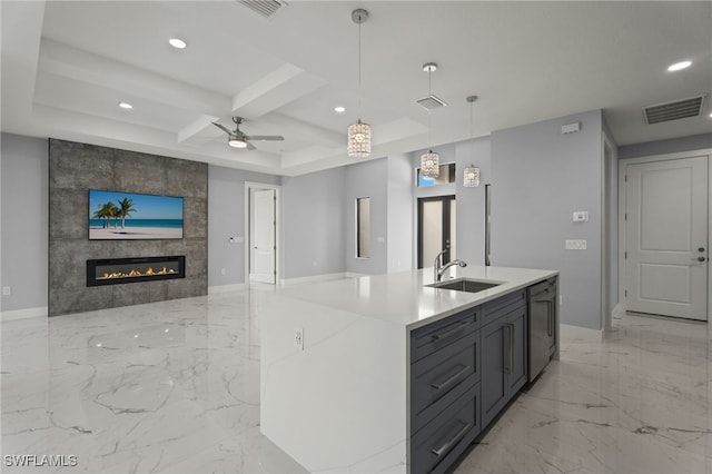 kitchen with beamed ceiling, sink, hanging light fixtures, a center island with sink, and coffered ceiling