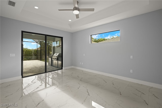 unfurnished room with ceiling fan, a raised ceiling, and a healthy amount of sunlight