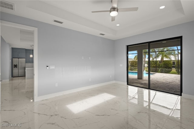 unfurnished room featuring ceiling fan and a tray ceiling