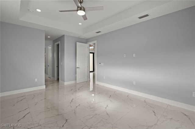 unfurnished room with ceiling fan and a raised ceiling