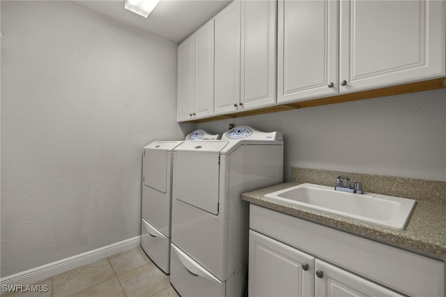 laundry room featuring light tile patterned flooring, cabinets, washer and clothes dryer, and sink