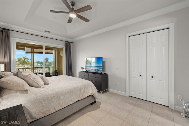 bedroom with light tile patterned floors, ceiling fan, access to exterior, a raised ceiling, and a closet