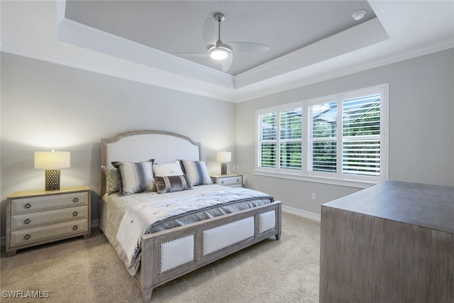 bedroom with ceiling fan, light carpet, and a tray ceiling