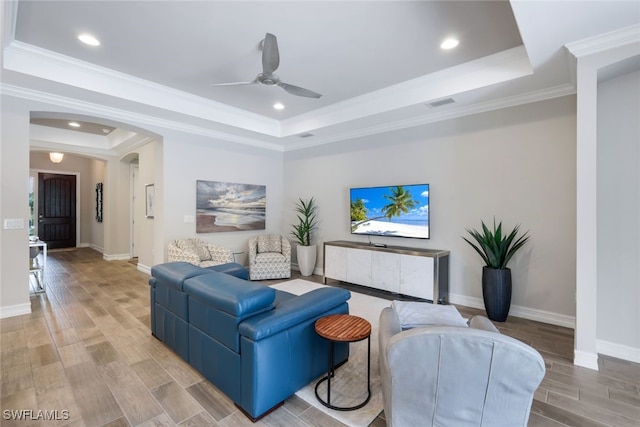 living room featuring ceiling fan, ornamental molding, and a tray ceiling