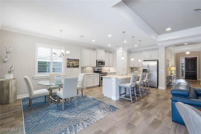 kitchen with white cabinets, an island with sink, decorative backsplash, pendant lighting, and appliances with stainless steel finishes