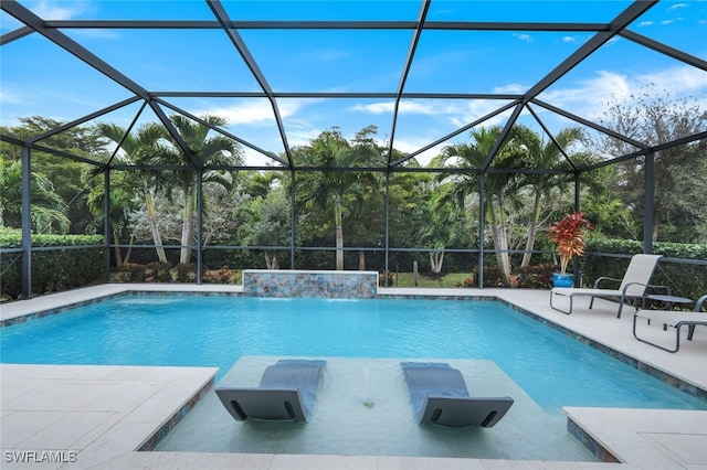 view of pool with a patio area, glass enclosure, and pool water feature