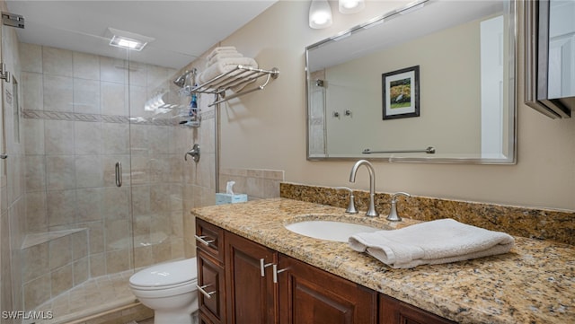 bathroom featuring toilet, a shower with door, and vanity