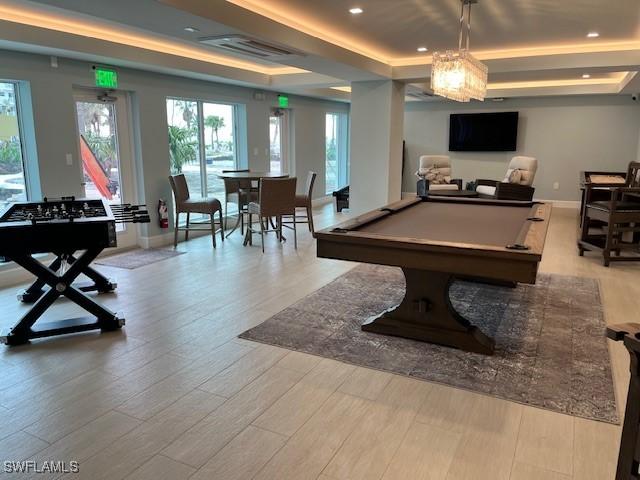 recreation room with a raised ceiling, light hardwood / wood-style floors, and billiards