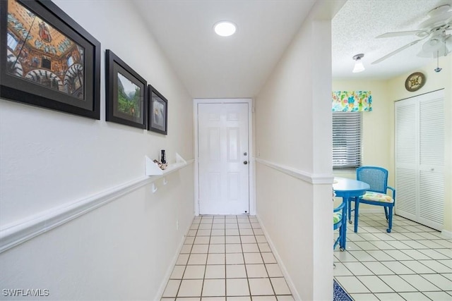 hall with light tile patterned flooring and a textured ceiling