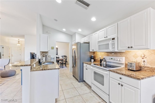 kitchen with white appliances, vaulted ceiling, kitchen peninsula, white cabinets, and sink