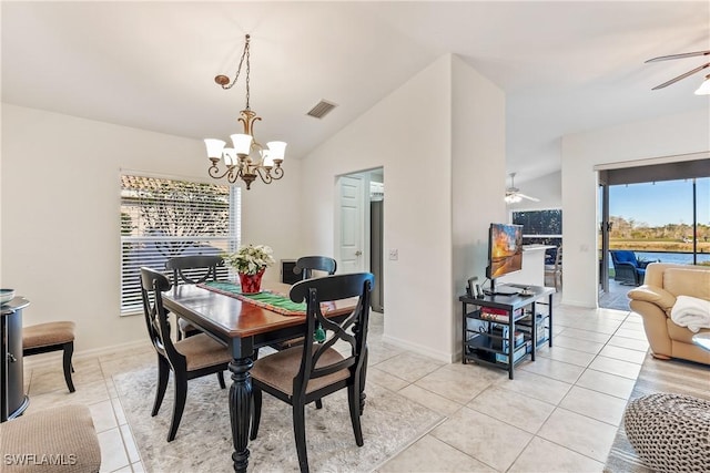 dining room with ceiling fan with notable chandelier, light tile patterned flooring, a wealth of natural light, and vaulted ceiling