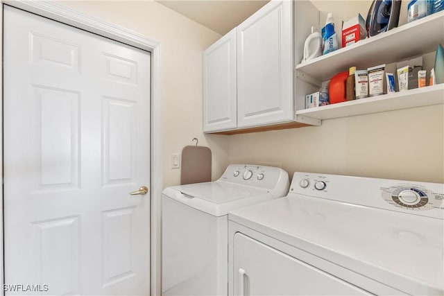 clothes washing area featuring cabinets and washing machine and dryer