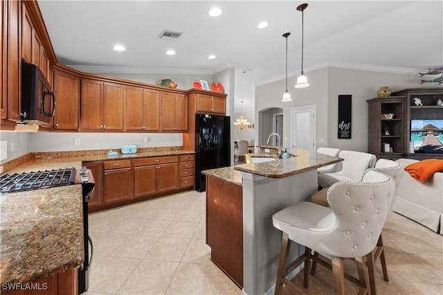 kitchen with pendant lighting, black appliances, a center island with sink, sink, and a breakfast bar area