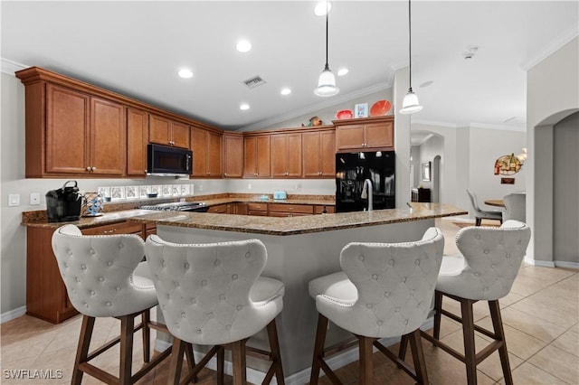 kitchen featuring pendant lighting, black appliances, vaulted ceiling, light tile patterned floors, and stone counters