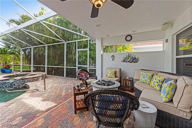 view of patio / terrace featuring ceiling fan, glass enclosure, and an outdoor living space with a fire pit