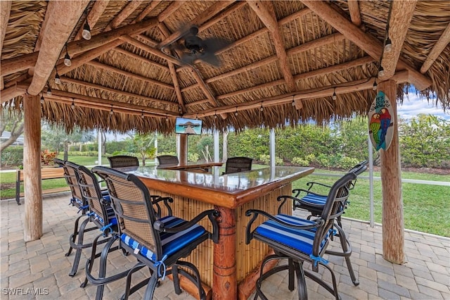 view of patio featuring ceiling fan, a gazebo, and a bar