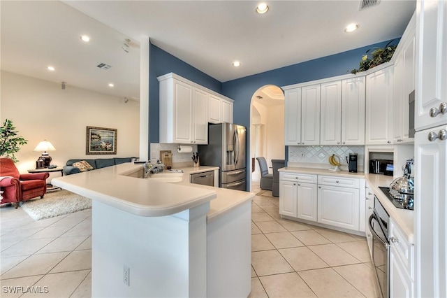 kitchen with appliances with stainless steel finishes, light tile patterned floors, white cabinetry, and kitchen peninsula