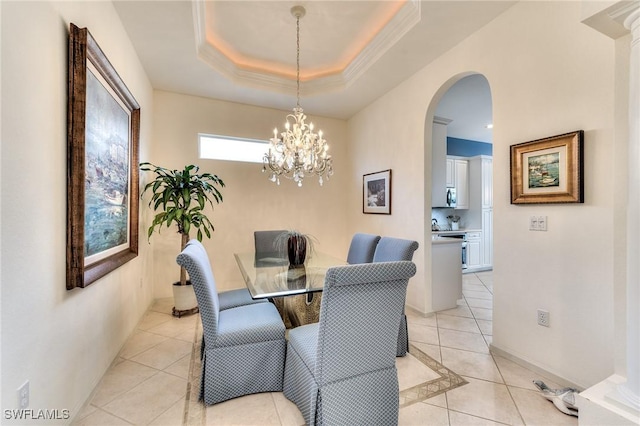 tiled dining room with ornamental molding, a raised ceiling, and an inviting chandelier