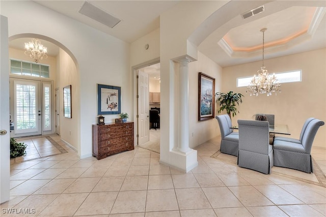 dining area with a raised ceiling, light tile patterned floors, plenty of natural light, and an inviting chandelier