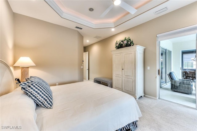 bedroom with ceiling fan, light colored carpet, and a tray ceiling