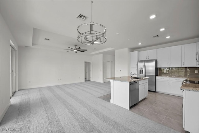 kitchen featuring stainless steel appliances, white cabinetry, ceiling fan, an island with sink, and hanging light fixtures