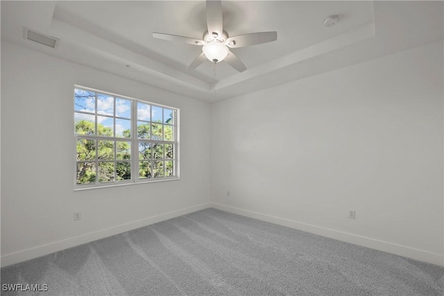 unfurnished room featuring ceiling fan, carpet floors, and a tray ceiling