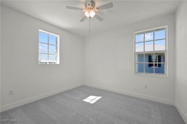 carpeted spare room featuring a healthy amount of sunlight and ceiling fan