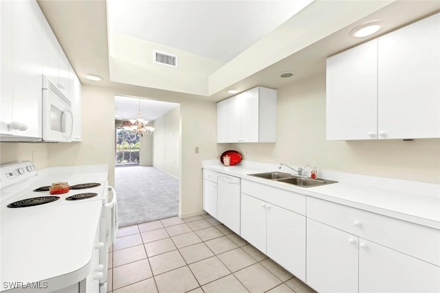 kitchen with sink, white appliances, light tile patterned floors, a notable chandelier, and white cabinets