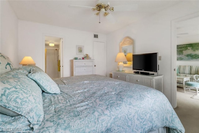 bedroom with ceiling fan, ensuite bath, and carpet flooring