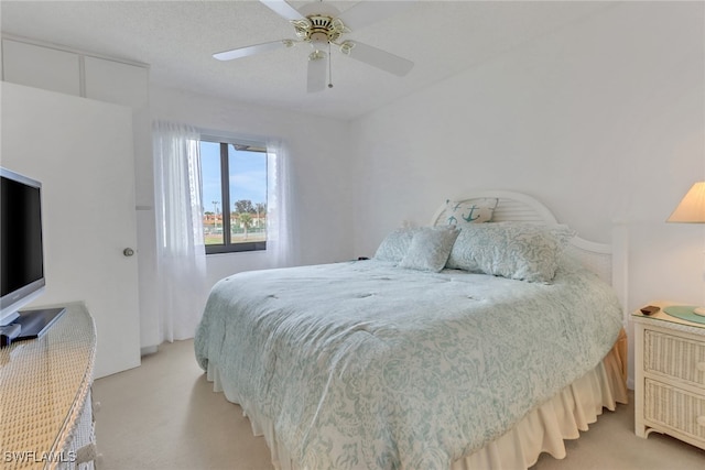 bedroom featuring light carpet, ceiling fan, and a textured ceiling