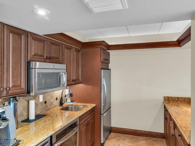 kitchen with light stone countertops, stainless steel appliances, tasteful backsplash, sink, and light tile patterned floors