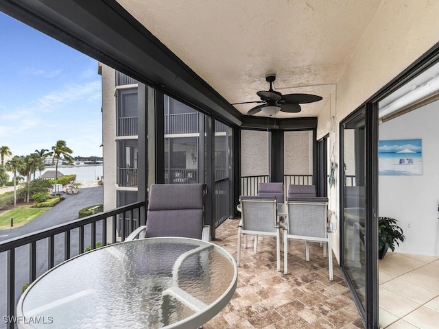 balcony with ceiling fan and a water view