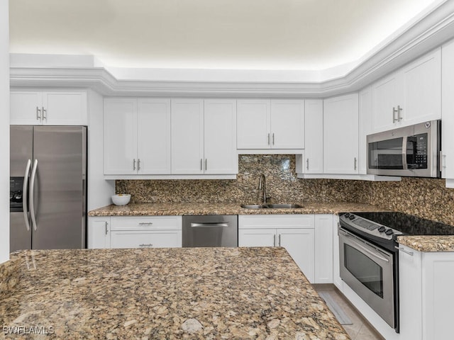 kitchen with white cabinets, stainless steel appliances, sink, and dark stone counters