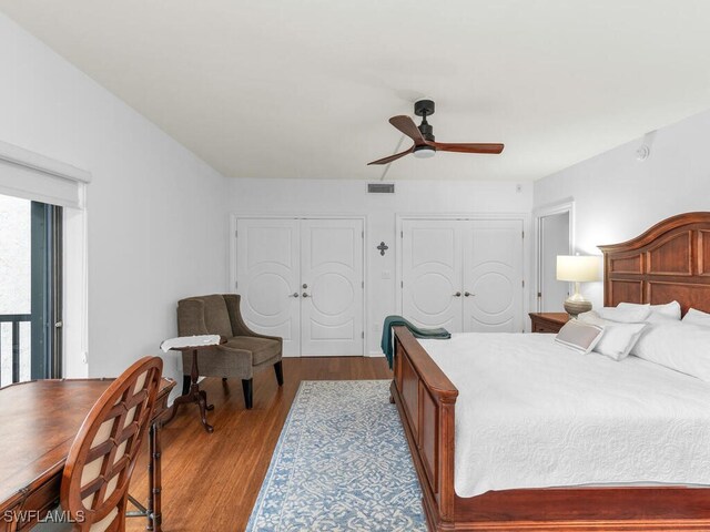 bedroom featuring ceiling fan, two closets, and light hardwood / wood-style floors