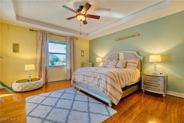 bedroom featuring a tray ceiling, ceiling fan, and hardwood / wood-style flooring