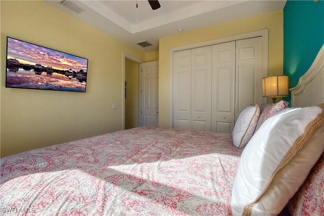 bedroom with ceiling fan, a tray ceiling, and a closet