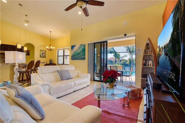 tiled living room with a towering ceiling and ceiling fan with notable chandelier