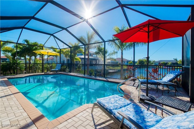 view of pool with a patio, a water view, and glass enclosure