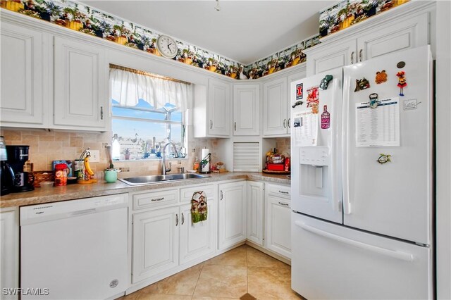 kitchen with light tile patterned floors, backsplash, white appliances, white cabinets, and sink