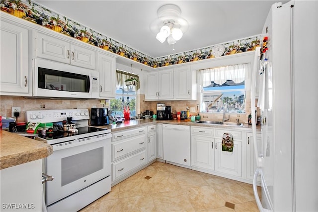 kitchen with a sink, backsplash, white cabinetry, white appliances, and light countertops